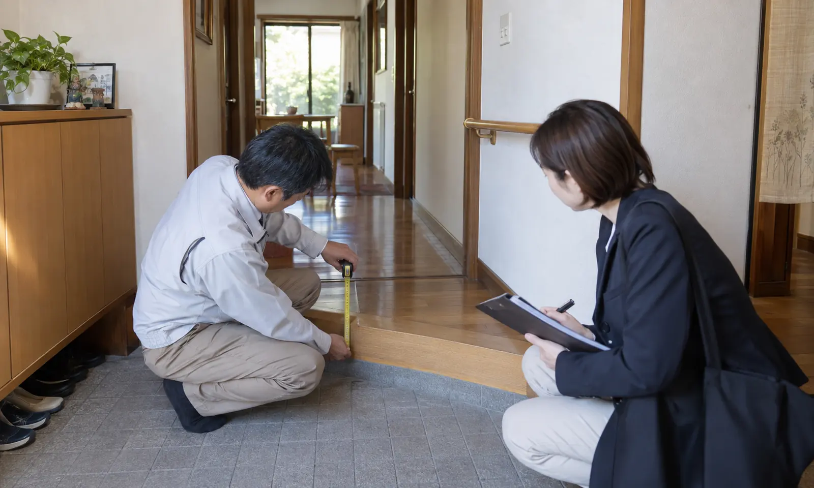 住宅の玄関段差を計測する住宅改修担当者